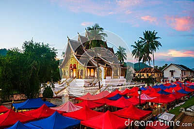 Famous night market in Luang Prabang, Laos with illuminated temple and sunset sky Stock Photo