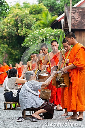 Luang Prabang, Laos - May 2019: Laotian people making offerings to Buddhist monks during alms giving ceremony Editorial Stock Photo