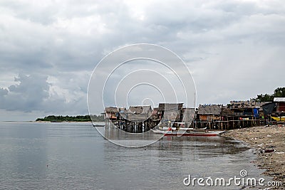 Small fishing boat anchored beside the over water stilt Bajau shanty houses. Long shot Editorial Stock Photo