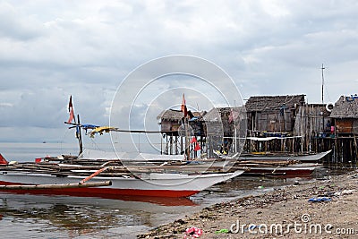 Small fishing boat anchored beside the over water stilt Bajau shanty houses. Long shot Editorial Stock Photo
