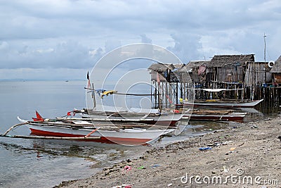 Small fishing boat anchored beside the over water stilt Bajau shanty houses. Long shot Editorial Stock Photo