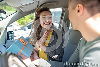 Happy woman looking at man with box in car Stock Photo