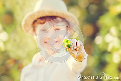 Lucky happy boy in hat holds four leaf clover Stock Photo