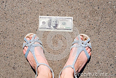 Lucky woman finding money on the street. Women feet next to hundred dollar bill. Lost and found money lying down on Stock Photo