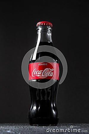 Lugansk, Ukraine - July 25, 2021: Coca Cola in glass bottle on dark background. Creative minimal concept Editorial Stock Photo