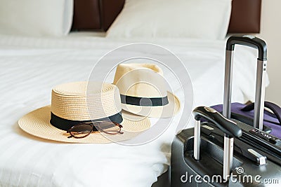 Luggage and hat of a couple on bed in modern hotel room with windows, curtains. Travel, relaxation, journey, trip and vacation Stock Photo