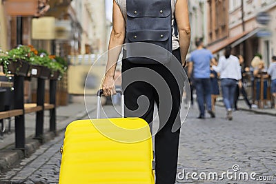 Luggage travel tourism concept, closeup of yellow suitcase in hand of walking woman Stock Photo