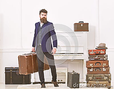 Luggage and vacation concept. Man, traveller with beard and mustache with luggage, luxury white interior background Stock Photo