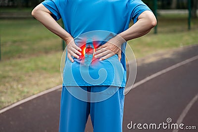 Lumbar intervertebral spine hernia, man with back pain on a running track after workout, spinal disc disease Stock Photo