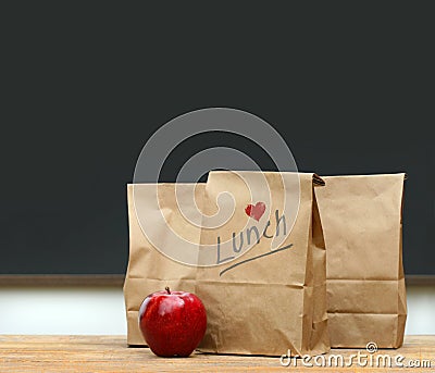 Lunch bags with apple on school desk Stock Photo