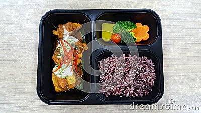 Lunch box with rice berry, vegetables, chicken, pumpkin, carrot, tomato, potato, block kerry in the black lunch box, healthy food Stock Photo