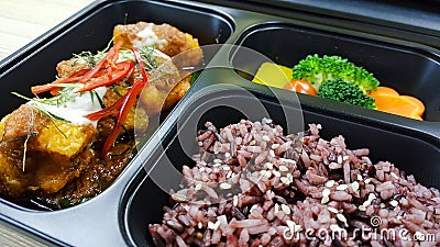 Lunch box with rice berry, vegetables, chicken, pumpkin, carrot, tomato, potato, block kerry in the black lunch box, healthy food Stock Photo