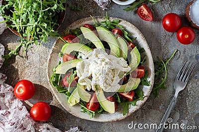Lunch dish: salad with avocado, cheese, arugula, cherry tomatoes and olive oil. Diet salad. View from above Stock Photo