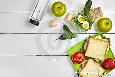Lunch. Green plate with sandwiches and fresh vegetables, bottle of water and green apple on wooden table. Healthy eating Stock Photo