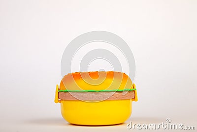 Lunchbox in the form of a yellow hamburger for preserving and carrying homemade food or sandwiches during working day. The symbol Stock Photo