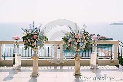 Lush bouquets of flowers in vases stand on small columns on the observation deck above the sea Stock Photo