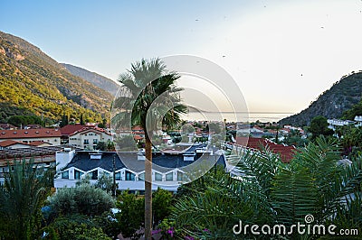 Lush mountaineous seaside town before sunset with paragliders Stock Photo