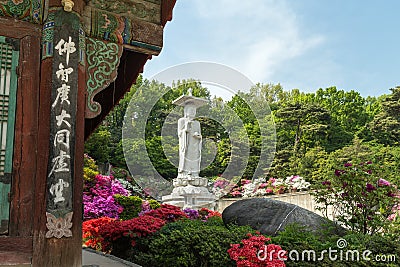 Lush vegetation and Buddha statue at the Bongeunsa Temple in Seoul Stock Photo