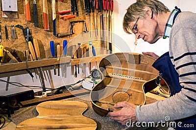 Luthier checking the body of an acoustic guitar Stock Photo