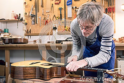 Luthier filing the frets of an acoustic guitar Stock Photo