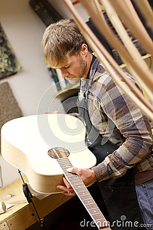 Luthier Inspecting Handmade Guitar in Workshop Stock Photo