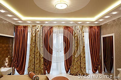 Luxurious bard curtains on the window of the mansion. Exit to the balcony. Square-shaped ceiling lighting Editorial Stock Photo
