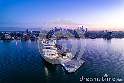 Luxurious cruise ship docked in a bustling metropolitan area, illuminated by the bright dawn sun Editorial Stock Photo