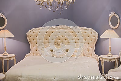 Luxurious expensive interior design of the children`s girl room in the old style. White bed, silk pillows, bedside tables with ta Stock Photo