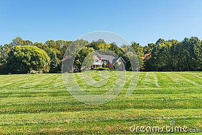 Luxurious large brick single family house surrounded by trees with a large green lawn. Landscape on a summer sunny day Stock Photo