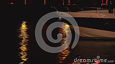 Luxurious modern private yacht and boat at the pier at night. Colorful lights of city glow shine reflected in water wave Stock Photo