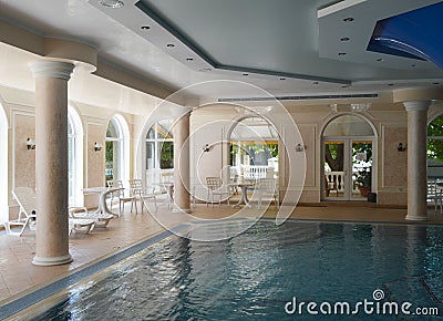 Luxurious pool interior design, sunlight from panoramic Windows, stylish columns and turquoise water Editorial Stock Photo