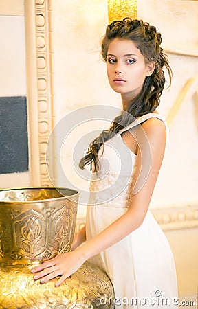 Luxurious Posh Brunette in White Dress. Oriental Antique Golden Decor Stock Photo