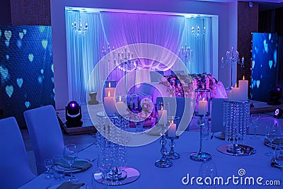 Luxurious wedding table with decor, with silver candlesticks, candles and flowers in blue light. Selective photo Stock Photo