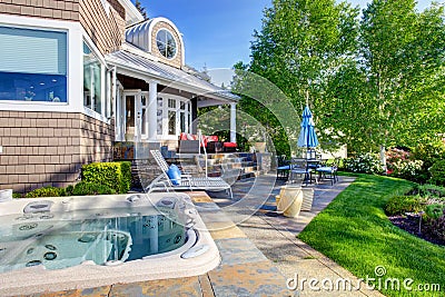 Luxury house exterior with impressive backyard design, patio area and hot tub. Stock Photo