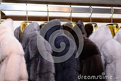 Luxury mink coats. Pink, grey, dark grey, pearl color fur coats on showcase of market. Stock Photo