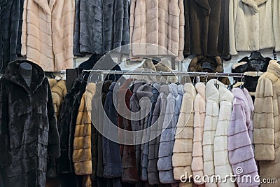 Luxury mink coats. Pink, grey, dark grey, pearl color fur coats on showcase of market. Best gift for a woman. Outerwear. Close up Stock Photo