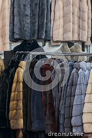 Luxury mink coats. Pink, grey, dark grey, pearl color fur coats on showcase of market. Best gift for a woman. Outerwear. Close up Stock Photo