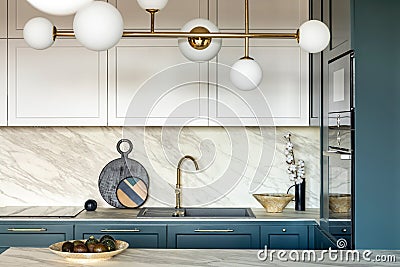 Luxury modern and vintage turquoise and white kitchen. Marble kitchen island with white owal chandelier . Gold tap on marble table Stock Photo