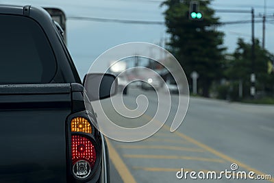 Luxury rear corner of pickup black car on the road with open brake light. Stock Photo