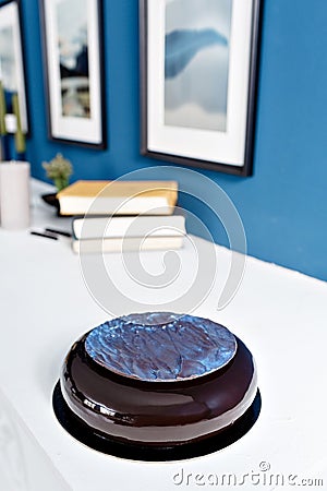 Luxury round chocolate dessert, with a blue disk on Black glaze. Mousse birthday cake with decor. on a wooden table Stock Photo