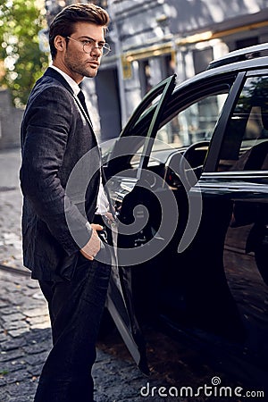 Luxury style. Handsome young businessman entering his car while standing outdoors Stock Photo