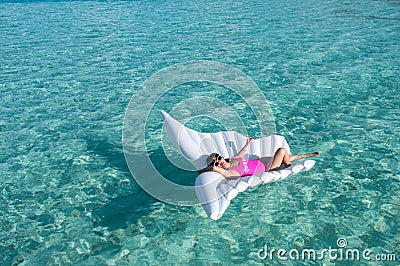 Luxury summer vacation beach woman relaxing lying down on inflatable pool float floating at Maldives sun tanning. Model sleeping o Stock Photo