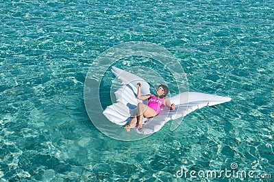 Luxury summer vacation beach woman relaxing lying down on inflatable pool float floating at Maldives sun tanning. Model sleeping o Stock Photo