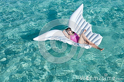 Luxury summer vacation beach woman relaxing lying down on inflatable pool float floating at Maldives sun tanning. Model sleeping o Stock Photo