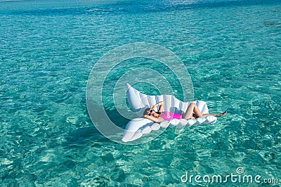 Luxury summer vacation beach woman relaxing lying down on inflatable pool float floating at Maldives sun tanning. Model sleeping o Stock Photo