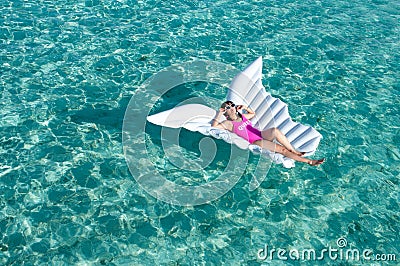 Luxury summer vacation beach woman relaxing lying down on inflatable pool float floating at Maldives sun tanning. Model sleeping o Stock Photo