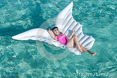 Luxury summer vacation beach woman relaxing lying down on inflatable pool float floating at Maldives sun tanning. Model sleeping o Stock Photo