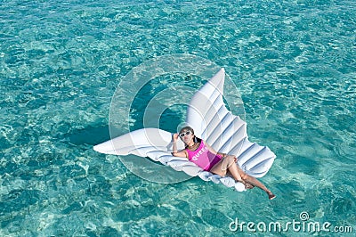 Luxury summer vacation beach woman relaxing lying down on inflatable pool float floating at Maldives sun tanning. Model sleeping o Stock Photo