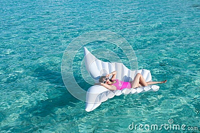 Luxury summer vacation beach woman relaxing lying down on inflatable pool float floating at Maldives sun tanning. Model sleeping o Stock Photo