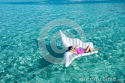 Luxury summer vacation beach woman relaxing lying down on inflatable pool float floating at Maldives sun tanning. Model sleeping o Stock Photo